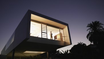 Exterior of a modern office building with man looking out window 